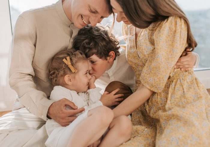 A happy family of four sitting together and sharing a loving moment indoors.