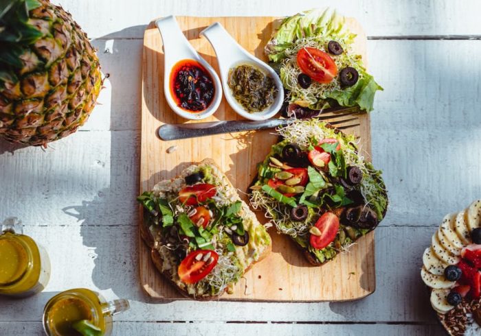 Top view of a vibrant and healthy brunch spread with sandwiches, fruits, and juices on a wooden table.