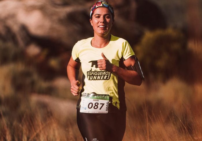 Woman runner in a bright yellow shirt smiling during an outdoor marathon race.